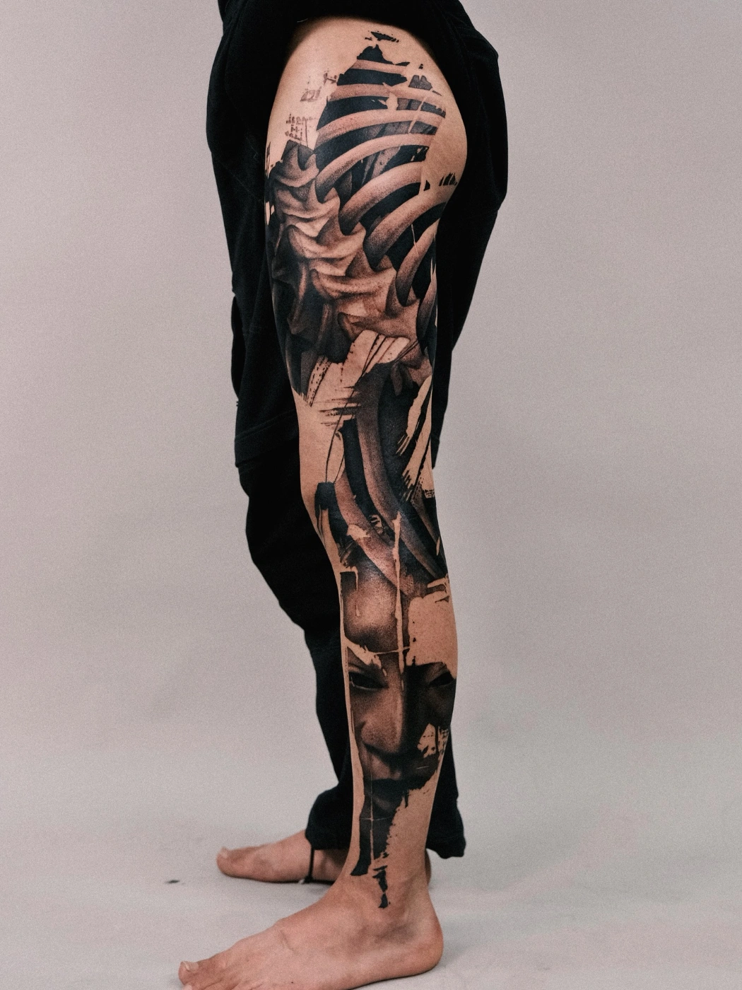 Detailed black-and-grey rib cage and face tattoo on leg.