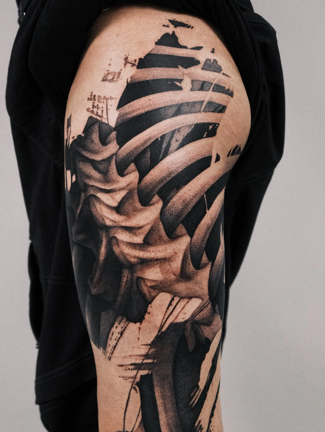 Detailed black-and-grey rib cage tattoo on thigh.