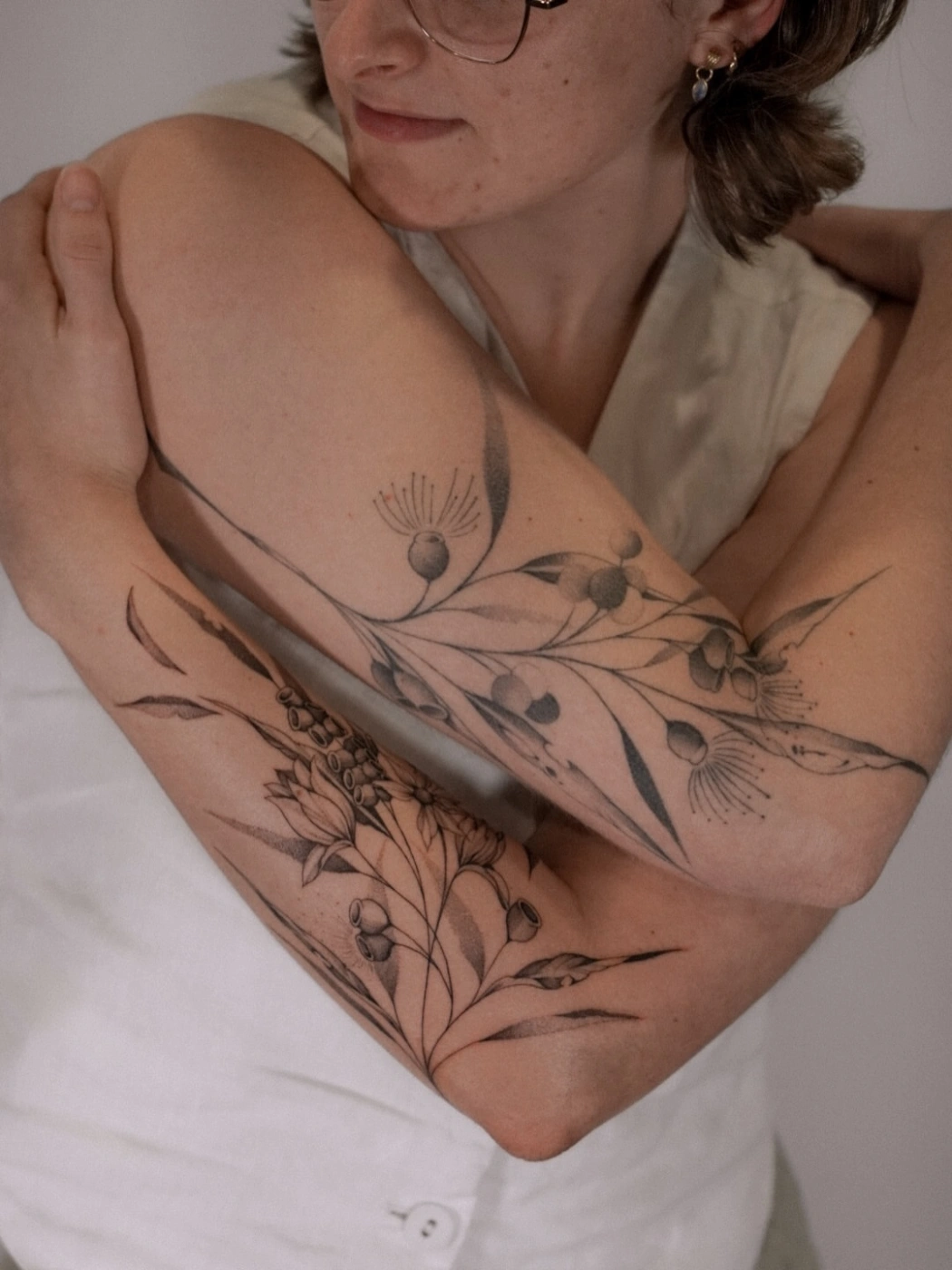 Large black-and-grey botanical tattoo on forearm.