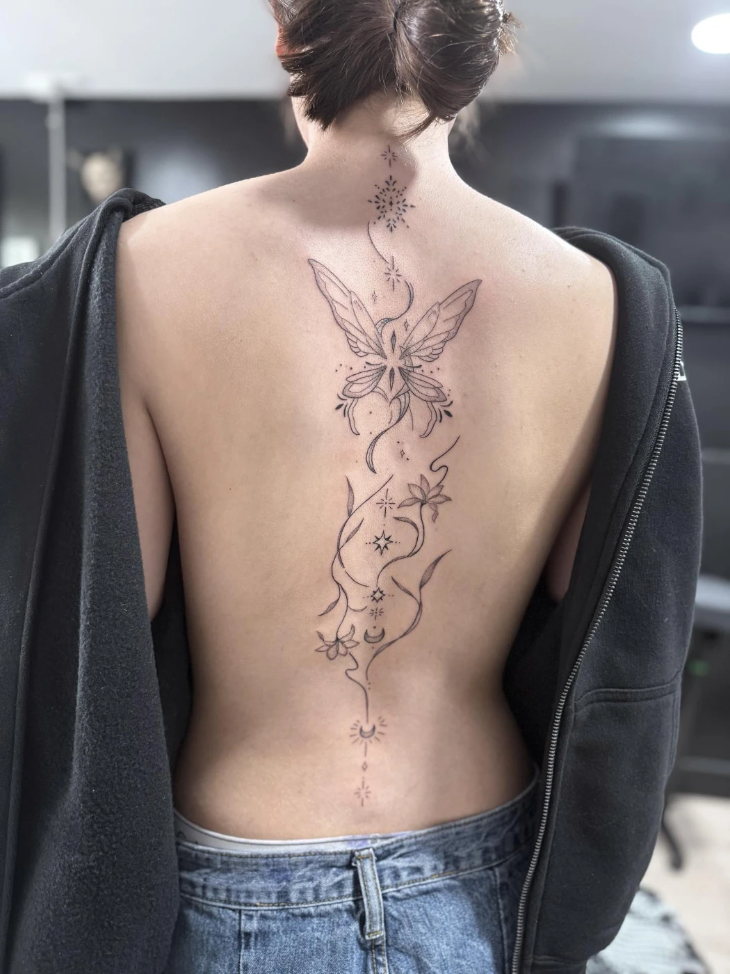 Large fine-line butterfly and floral tattoo on the back.
