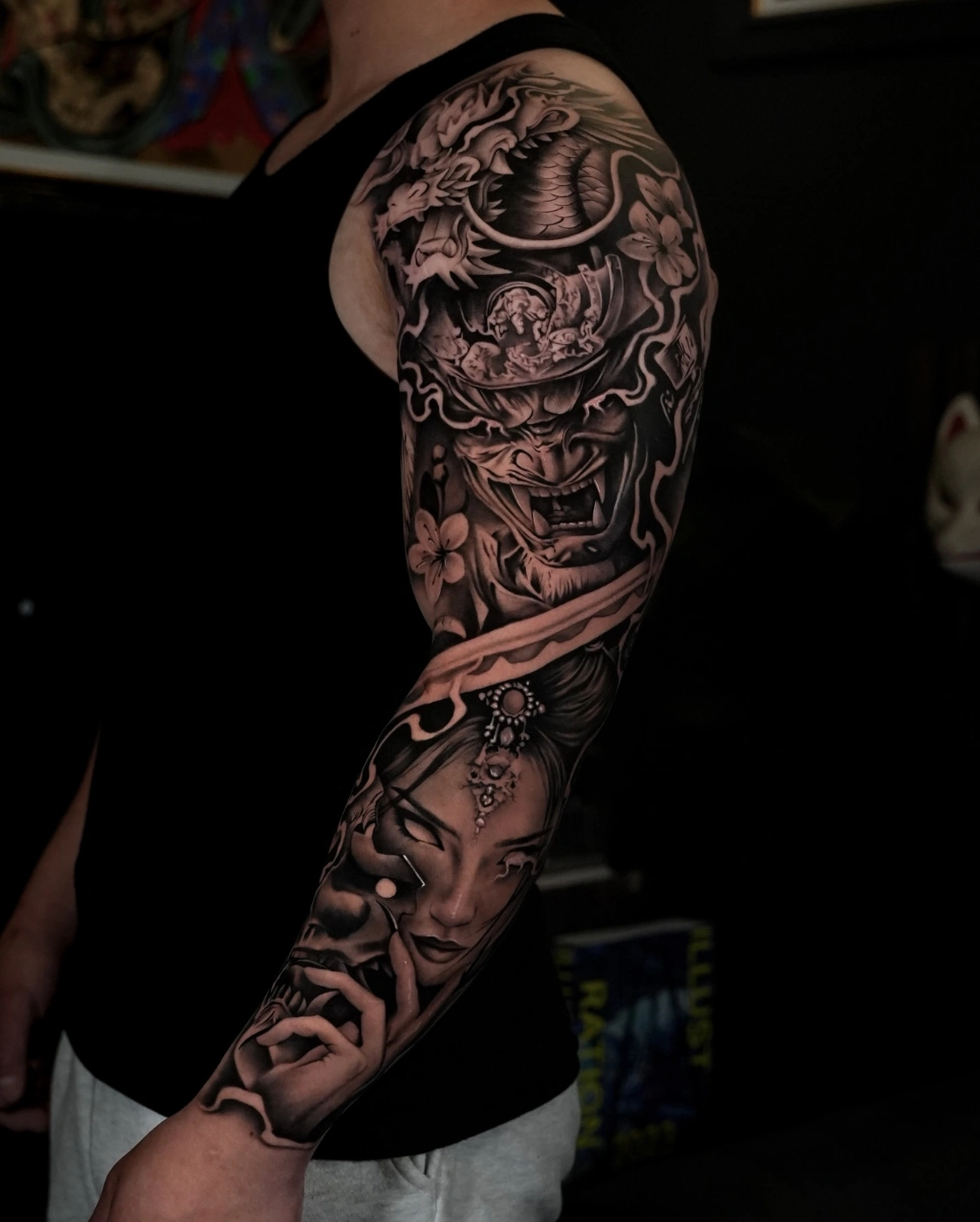 Detailed black-and-grey full-sleeve tattoo featuring mythical creatures.