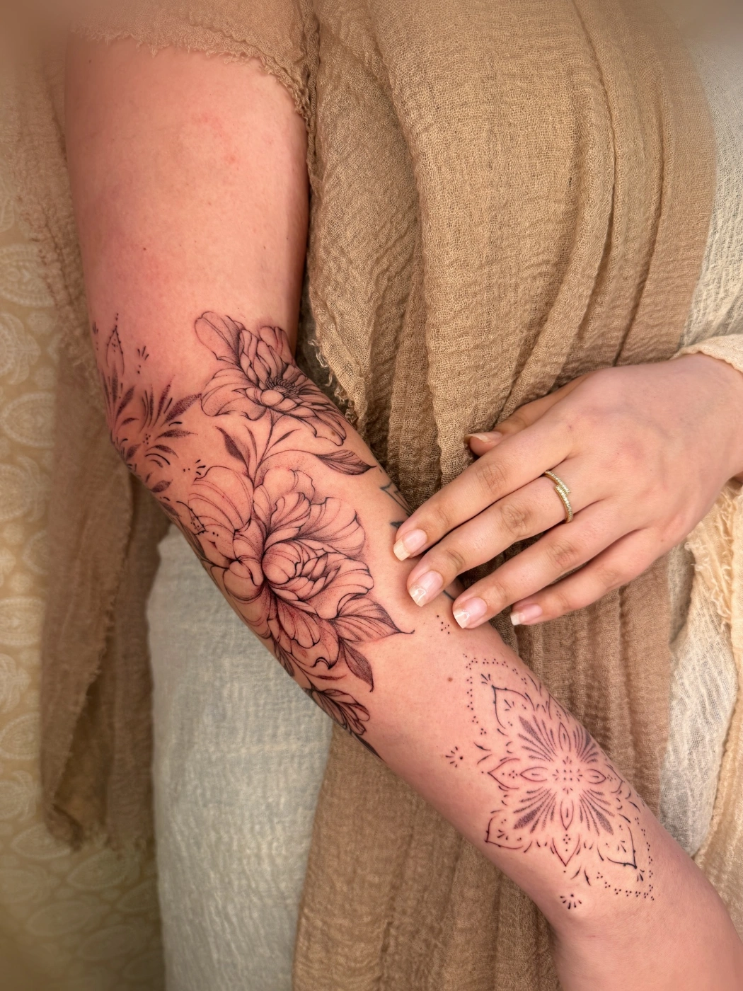 Large floral tattoo on a forearm with black-and-grey and watercolor elements.