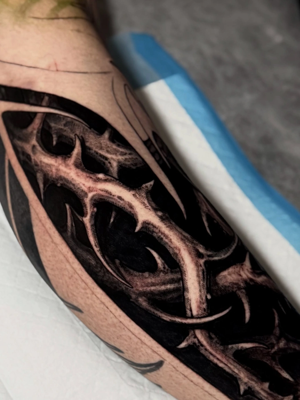 Large blackwork tattoo with abstract shapes on arm.