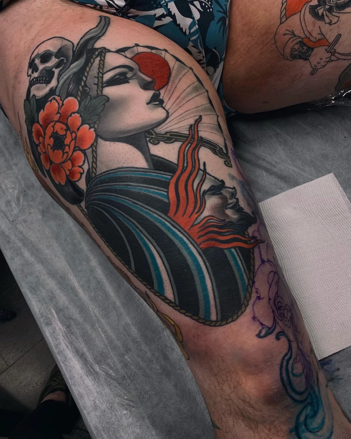 Colorful thigh tattoo of a geisha with a skull and flower.