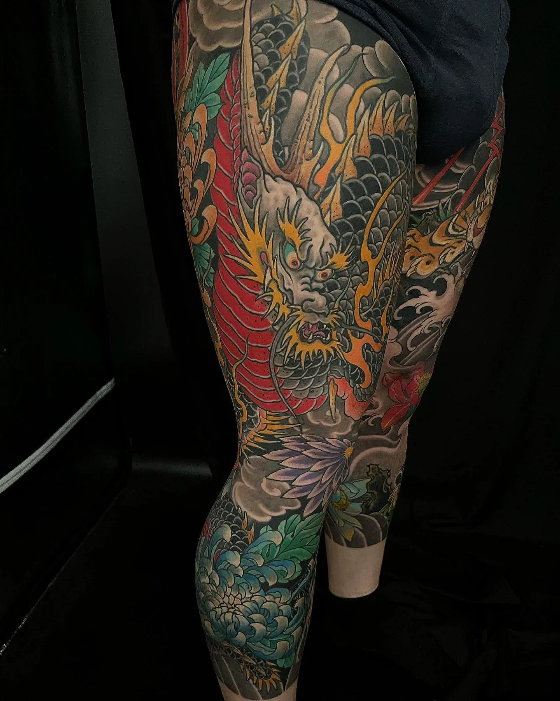 Large colorful Japanese dragon tattoo on thigh and leg.