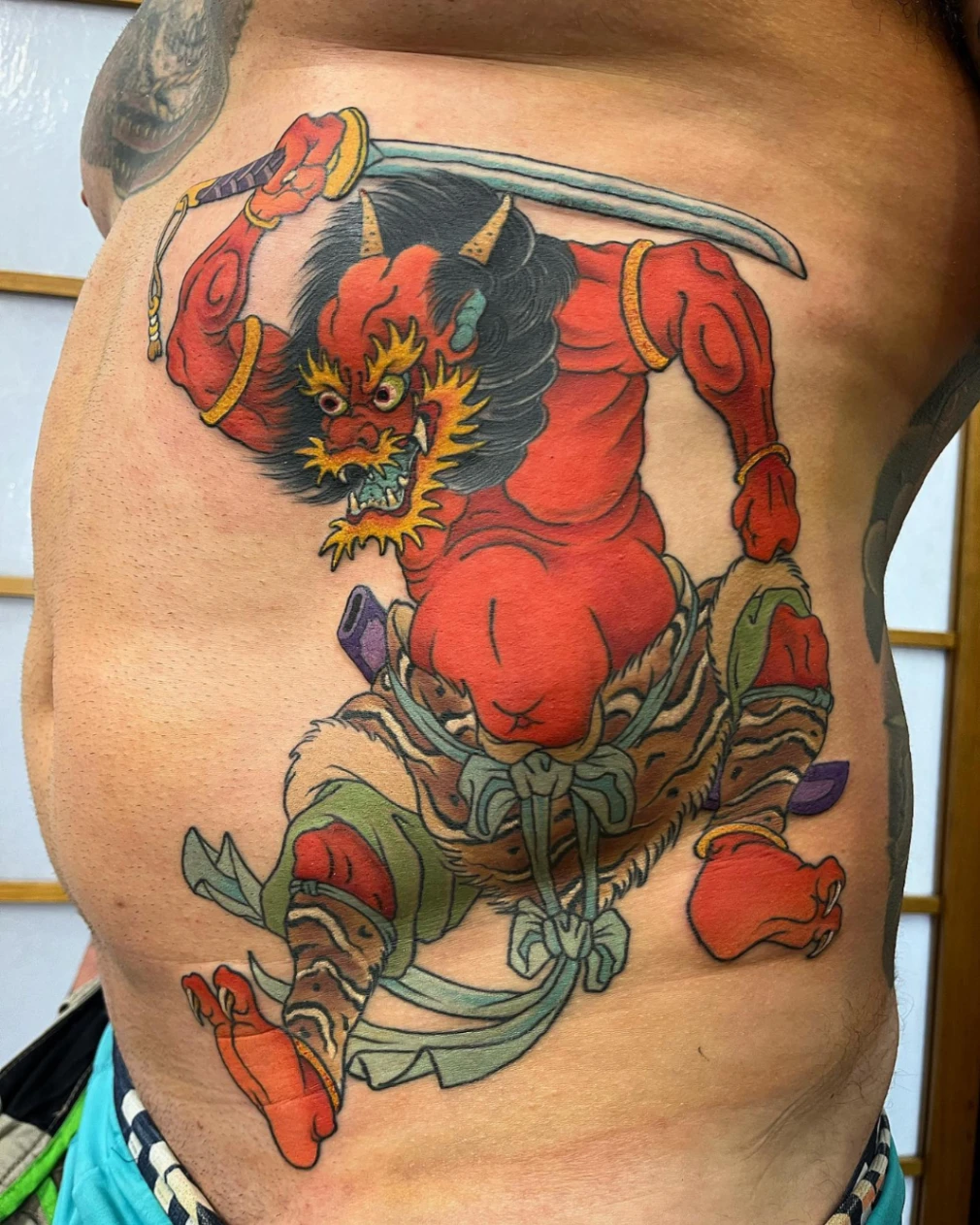 Large colorful oni tattoo on chest and rib.
