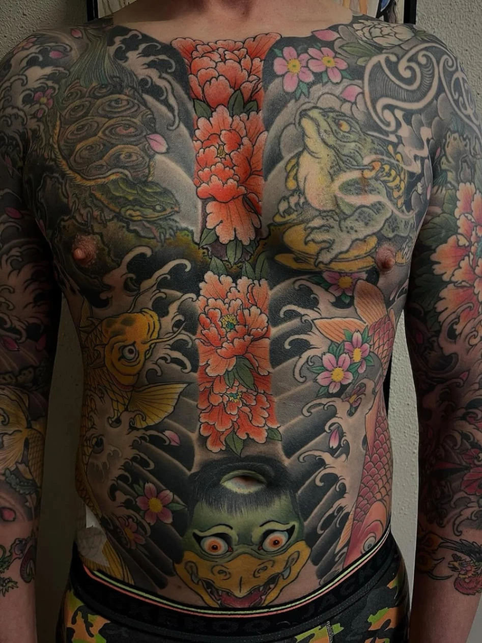 Large Japanese tattoo featuring dragons and flowers on chest and arms.