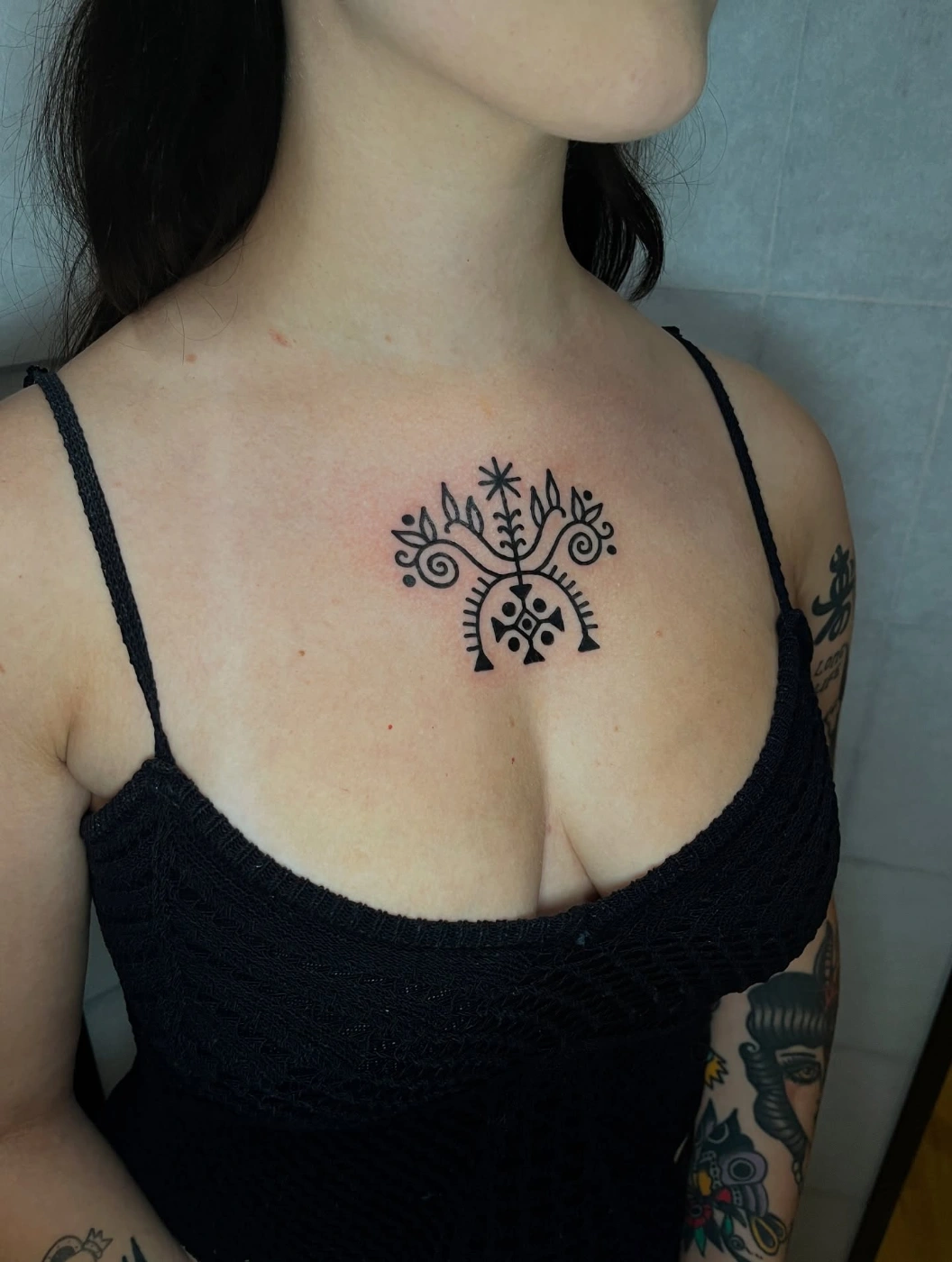 Abstract blackwork tattoo on chest with floral and geometric elements.