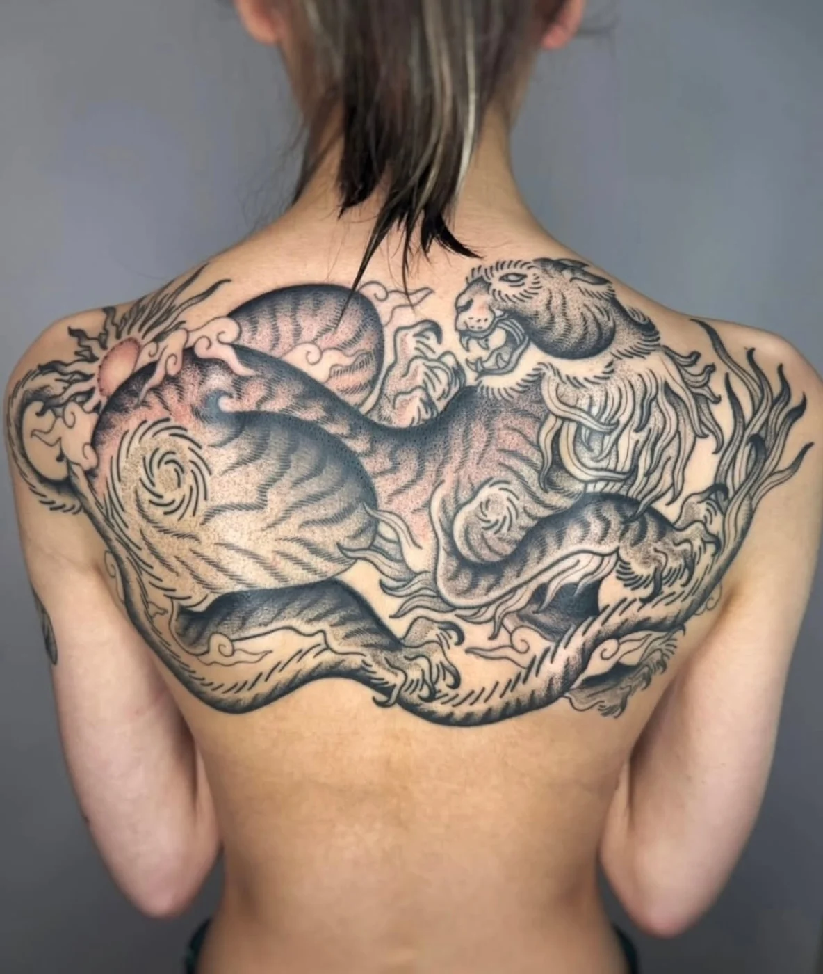 Large black-and-grey dragon and tiger tattoo on back.