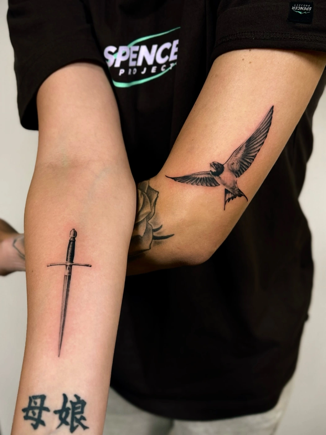 Detailed sword and bird tattoos on forearm and bicep.