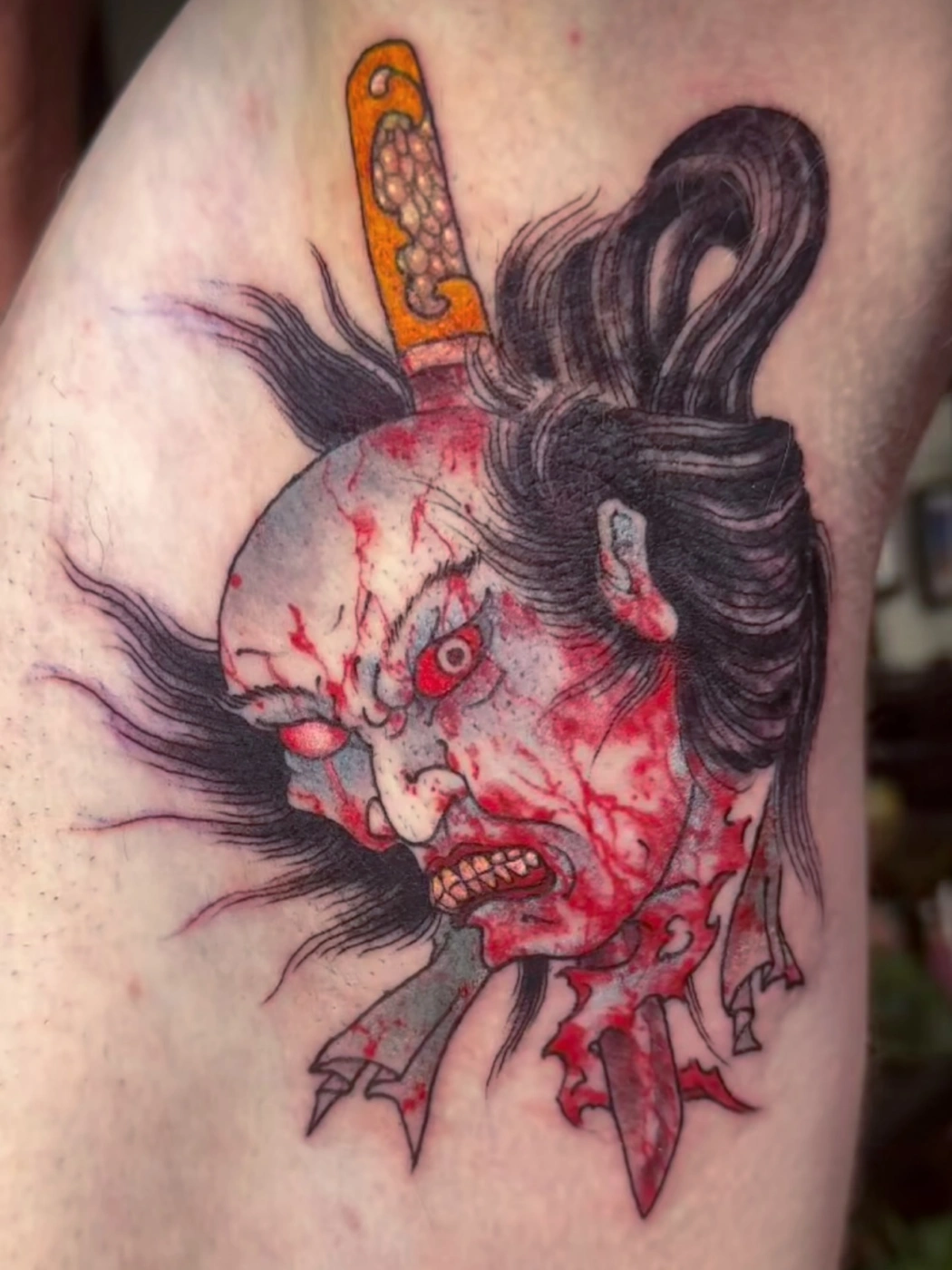 Illustrative samurai face tattoo with blood details on arm.