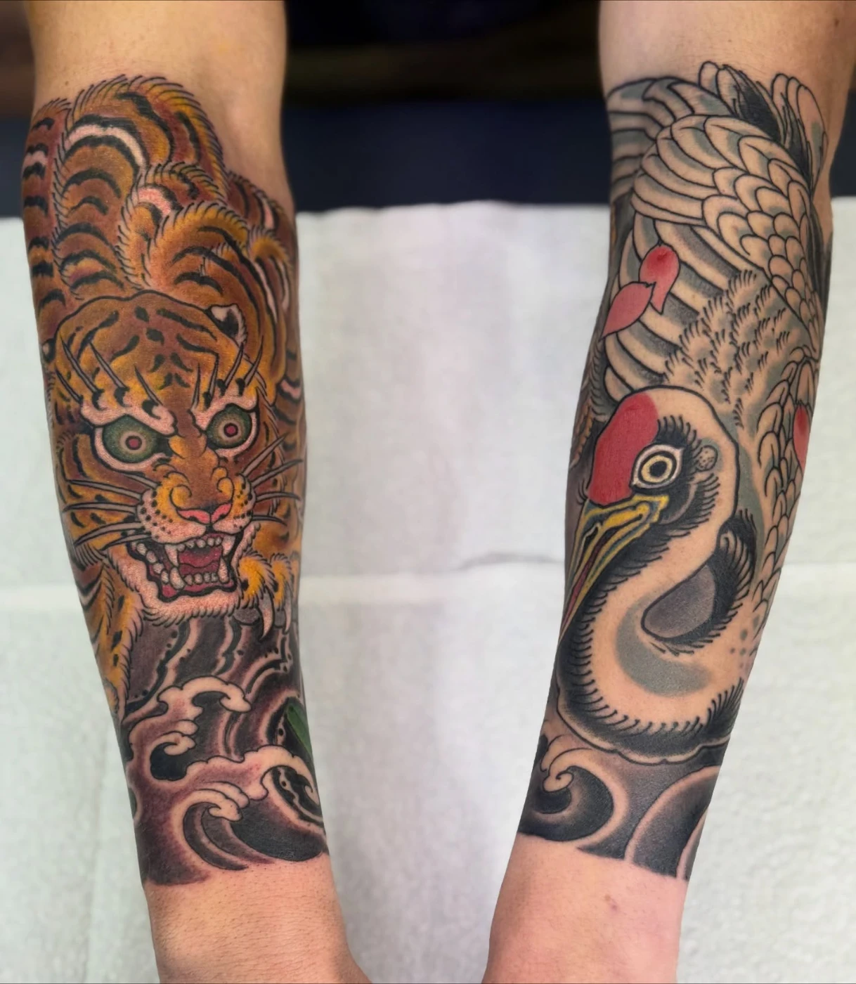 Colorful tiger and crane tattoo on forearm.