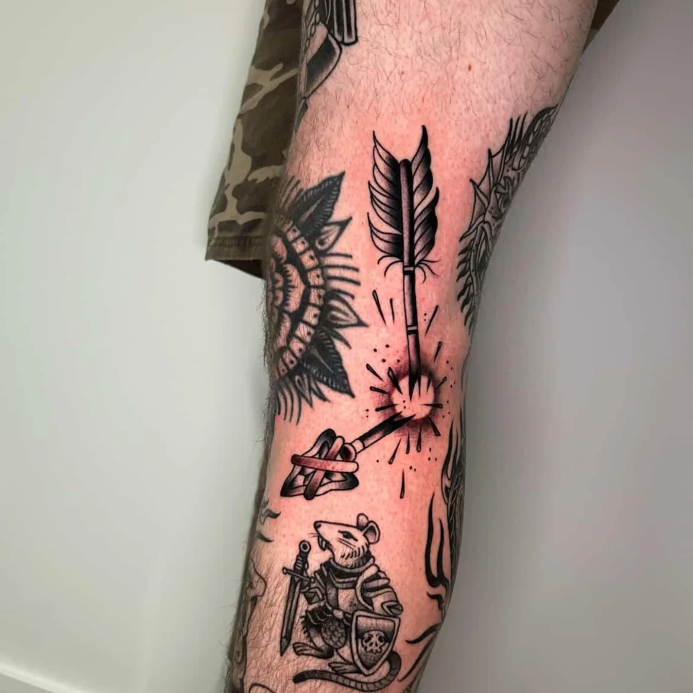 Illustrative tattoo of an arrow and mouse on a calf.