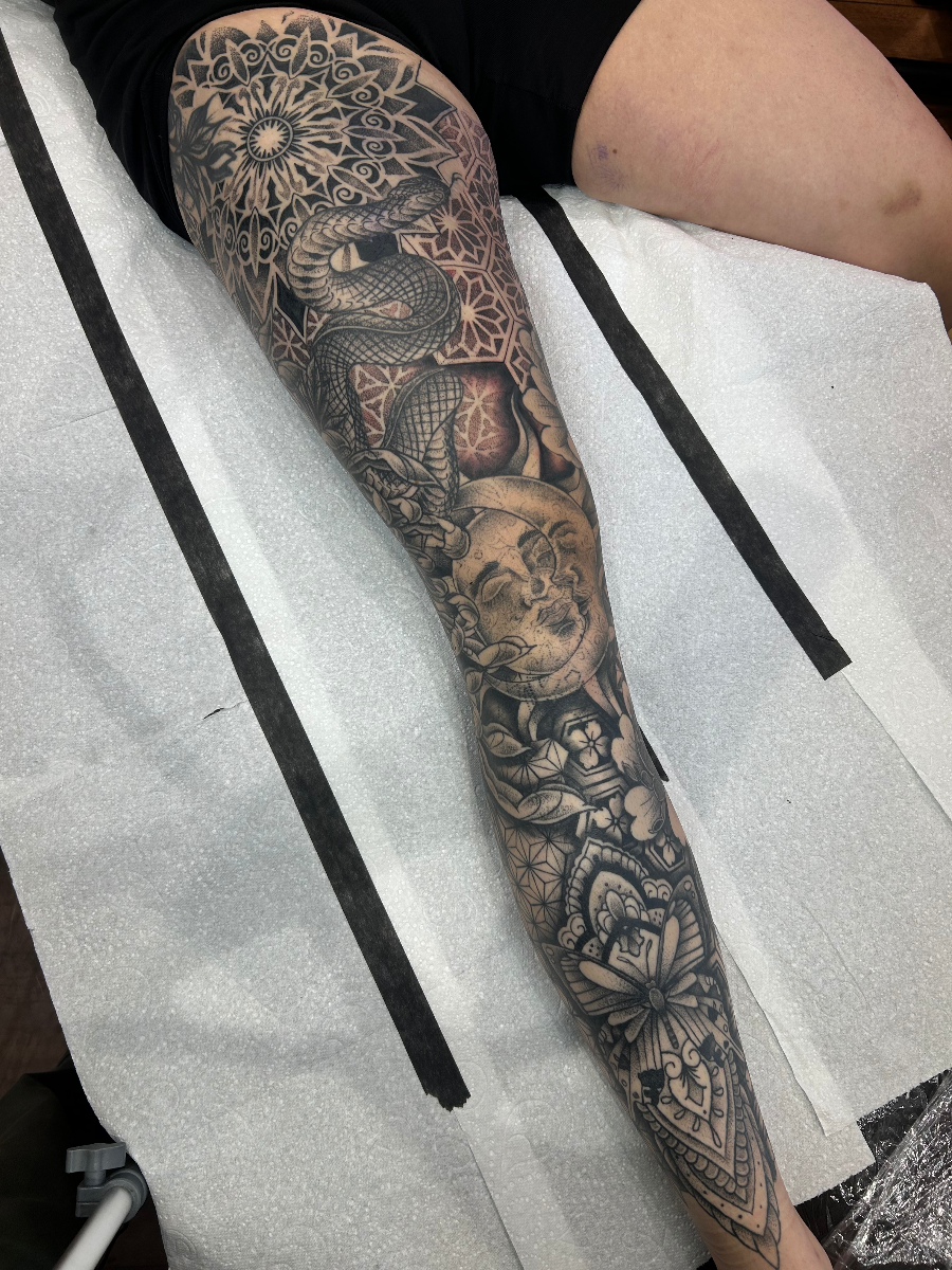 Full-sleeve black and grey tattoo featuring a snake and mandala.