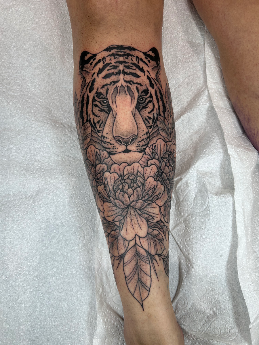 Realistic tiger tattoo with flowers on calf.