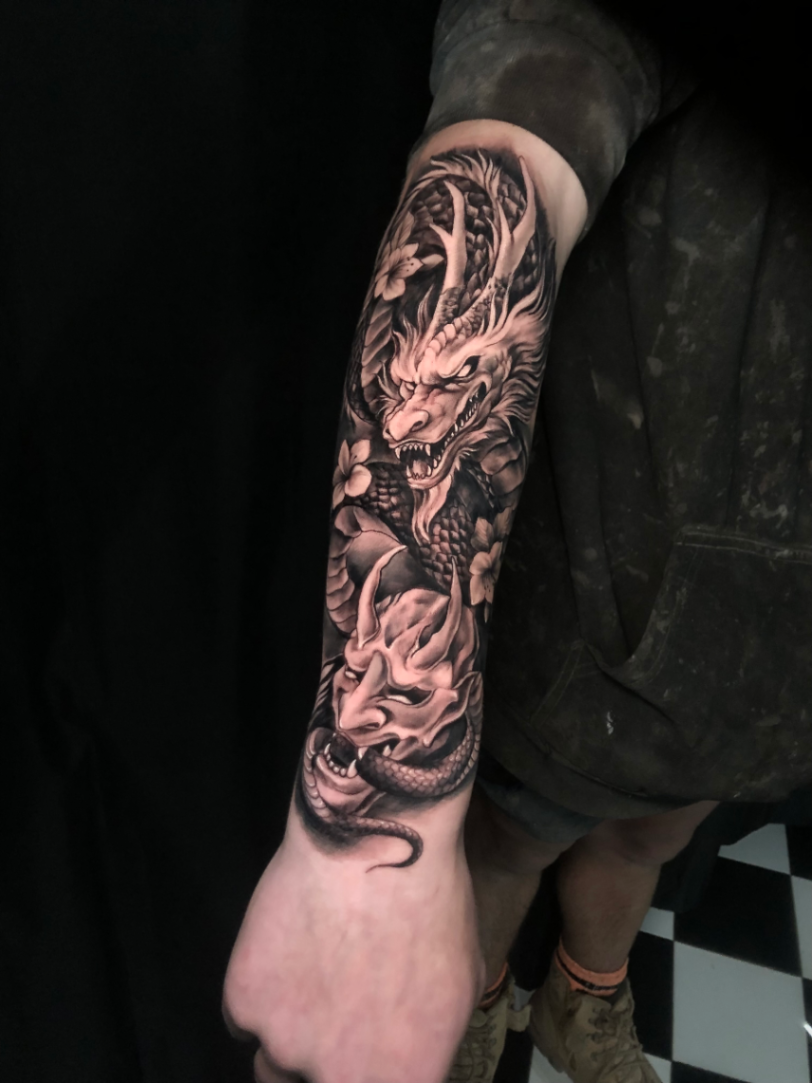 Large black-and-grey dragon tattoo on forearm.