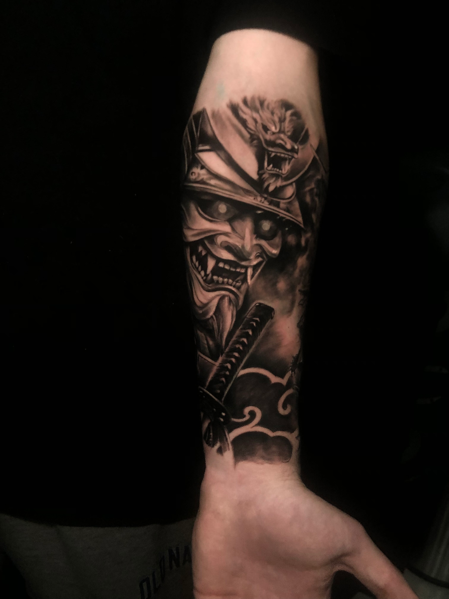 Detailed samurai tattoo on forearm with dragon and clouds.
