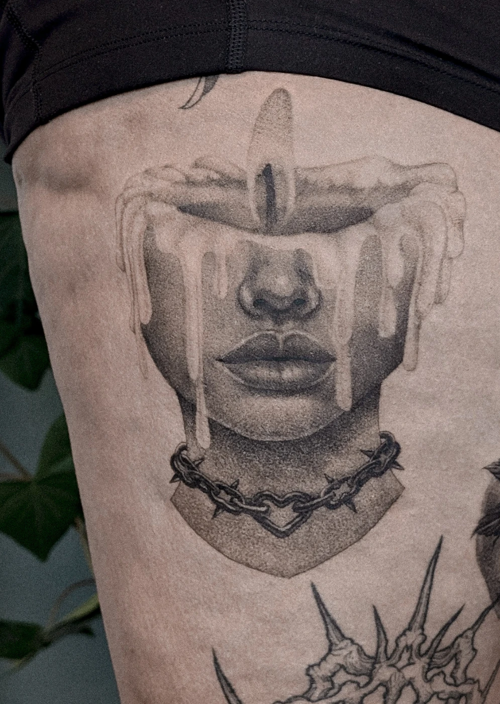 Realistic black-and-grey tattoo of a face with a melting candle.