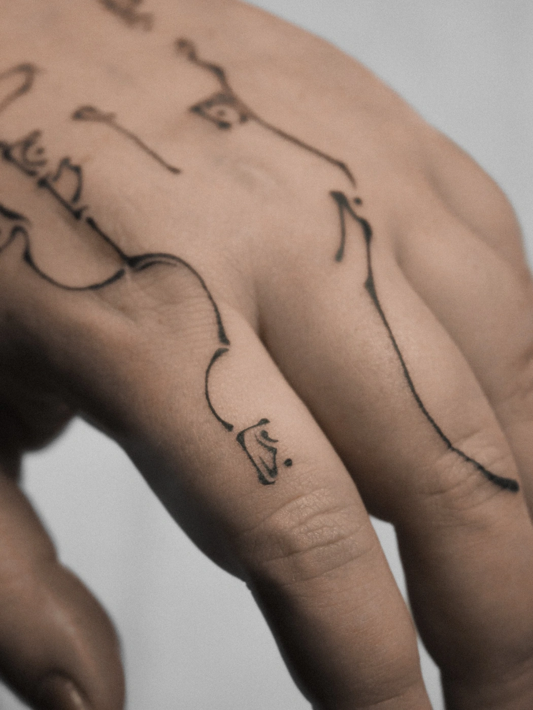 Fine-line abstract tattoo on a hand.