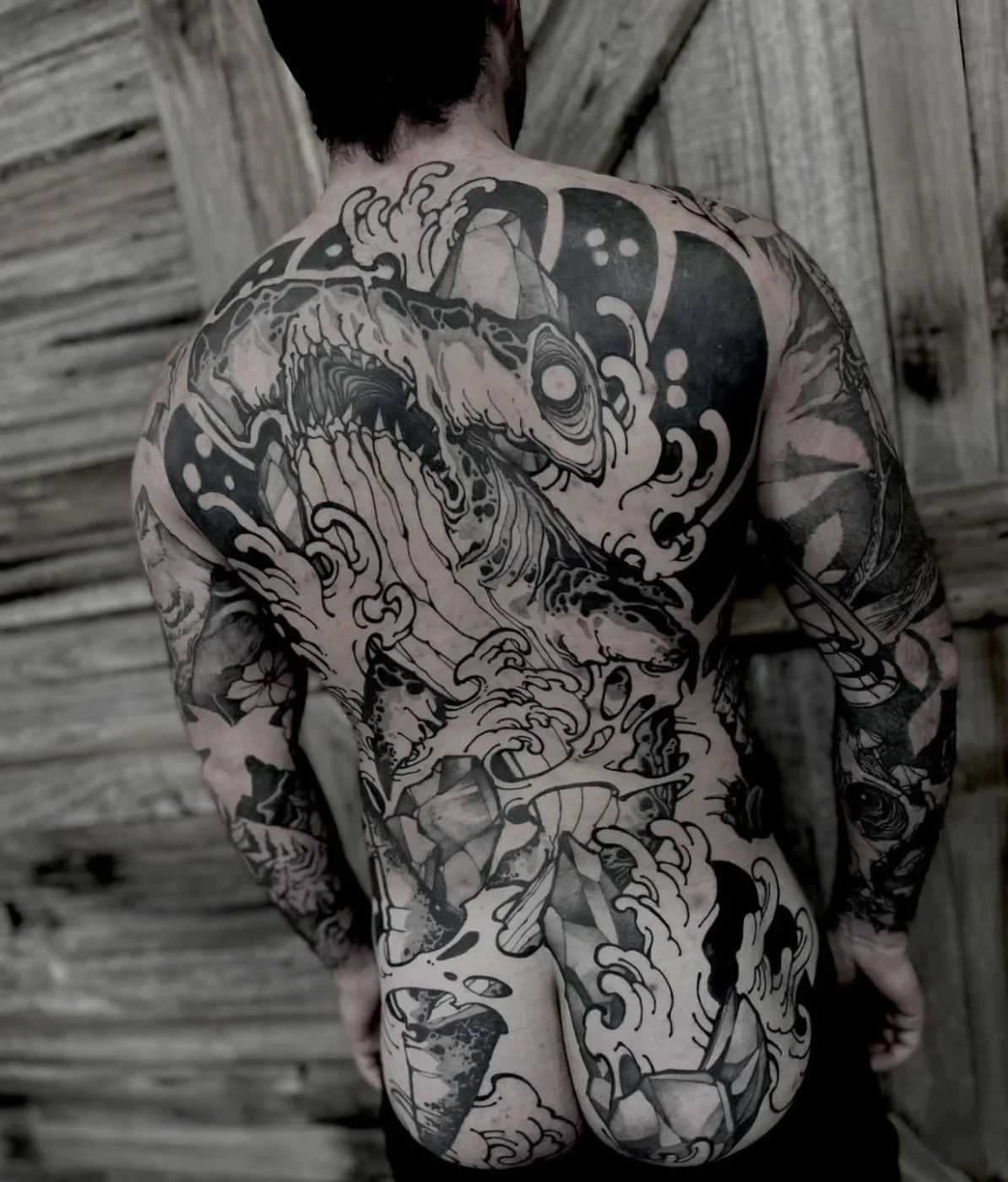 Large black-and-grey shark tattoo on a man's back.