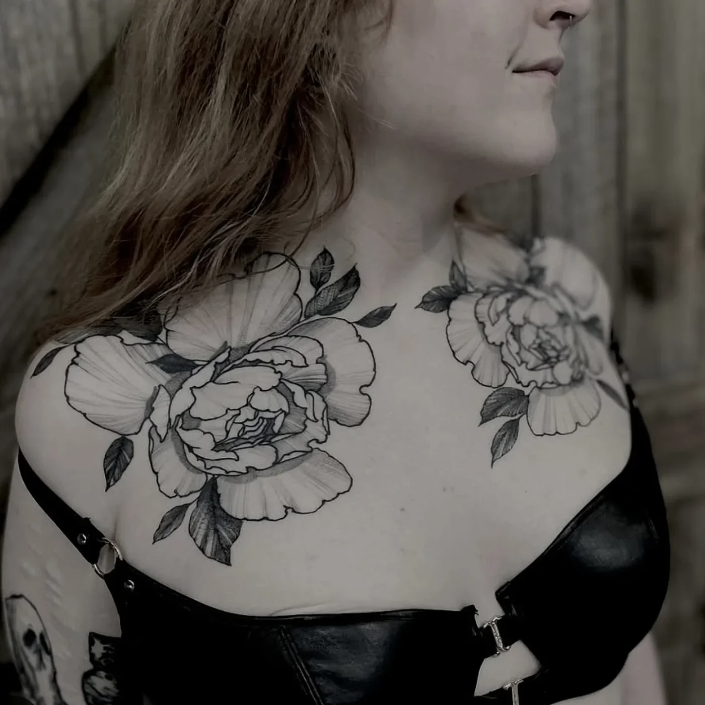 Large blackwork floral tattoo on chest and shoulder.
