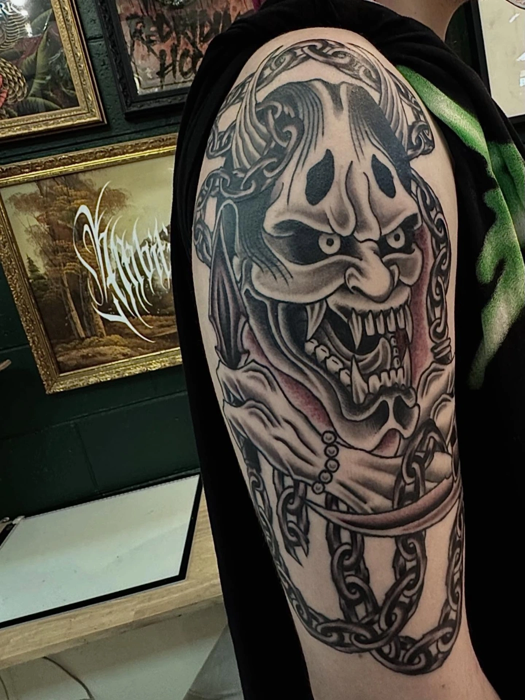Large black-and-grey demon tattoo on arm.