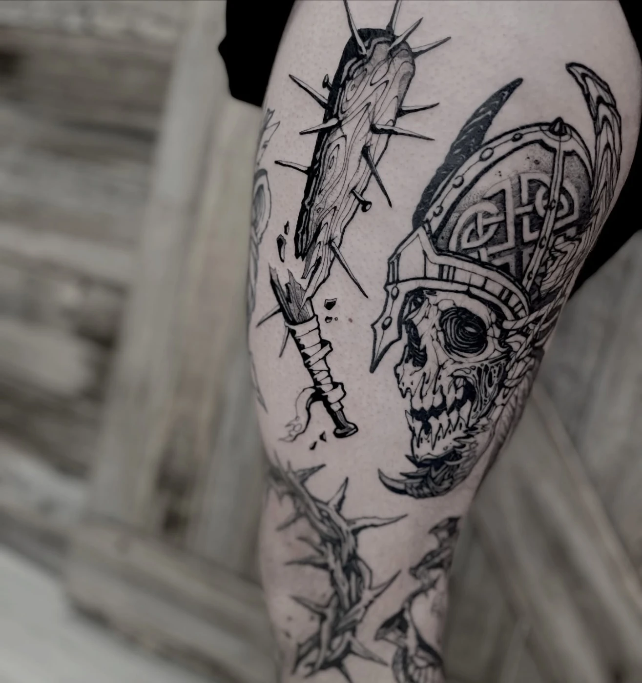 Detailed blackwork tattoo of a skull and sword on thigh.