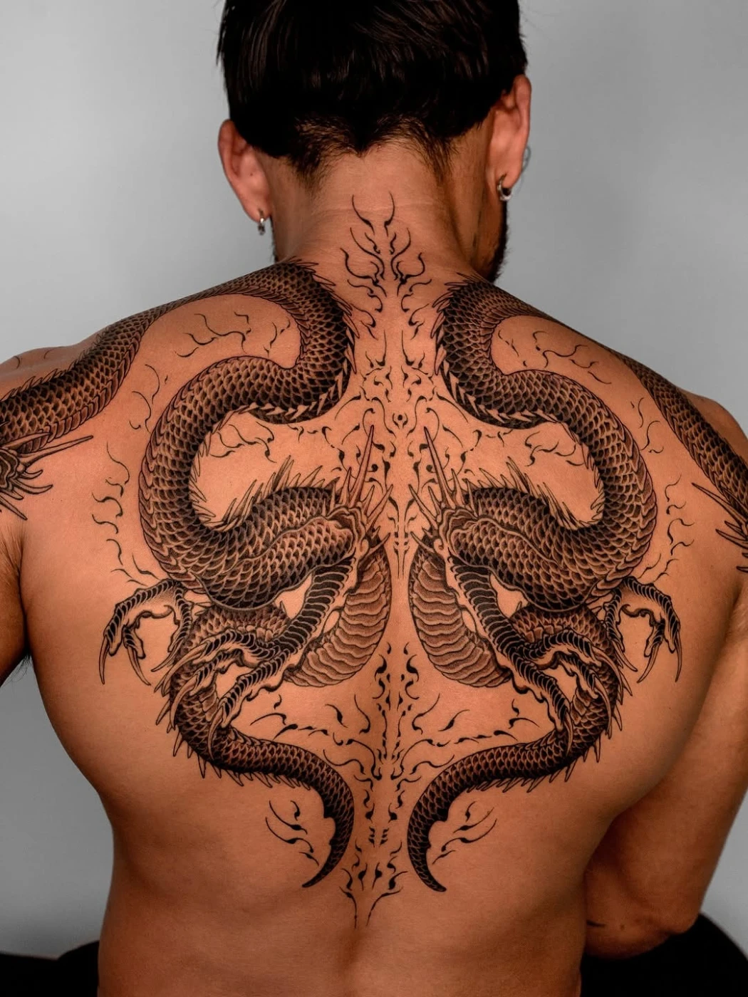 Large blackwork dragon tattoo on a man's back.