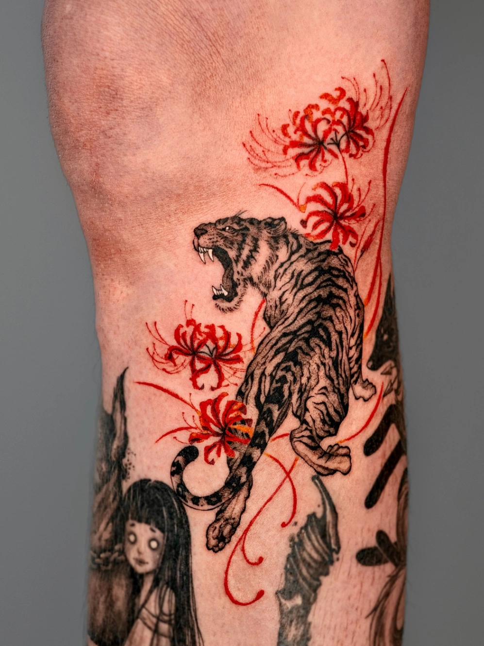Illustrative tiger tattoo with flowers on forearm.
