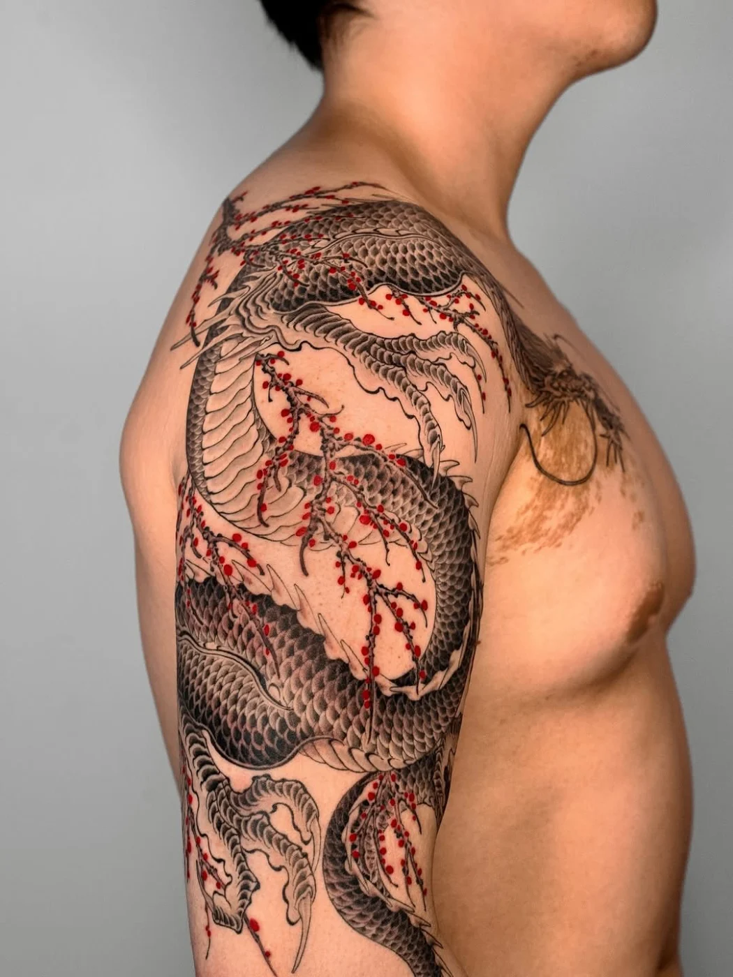 Japanese dragon tattoo with cherry blossoms on arm.