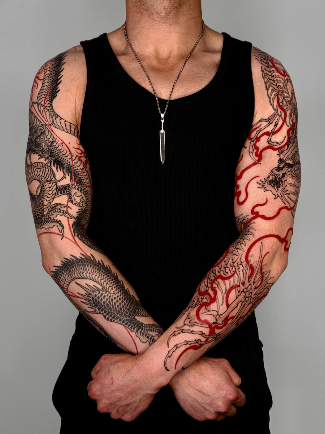 Full-sleeve tattoo of dragons and flames on an arm.