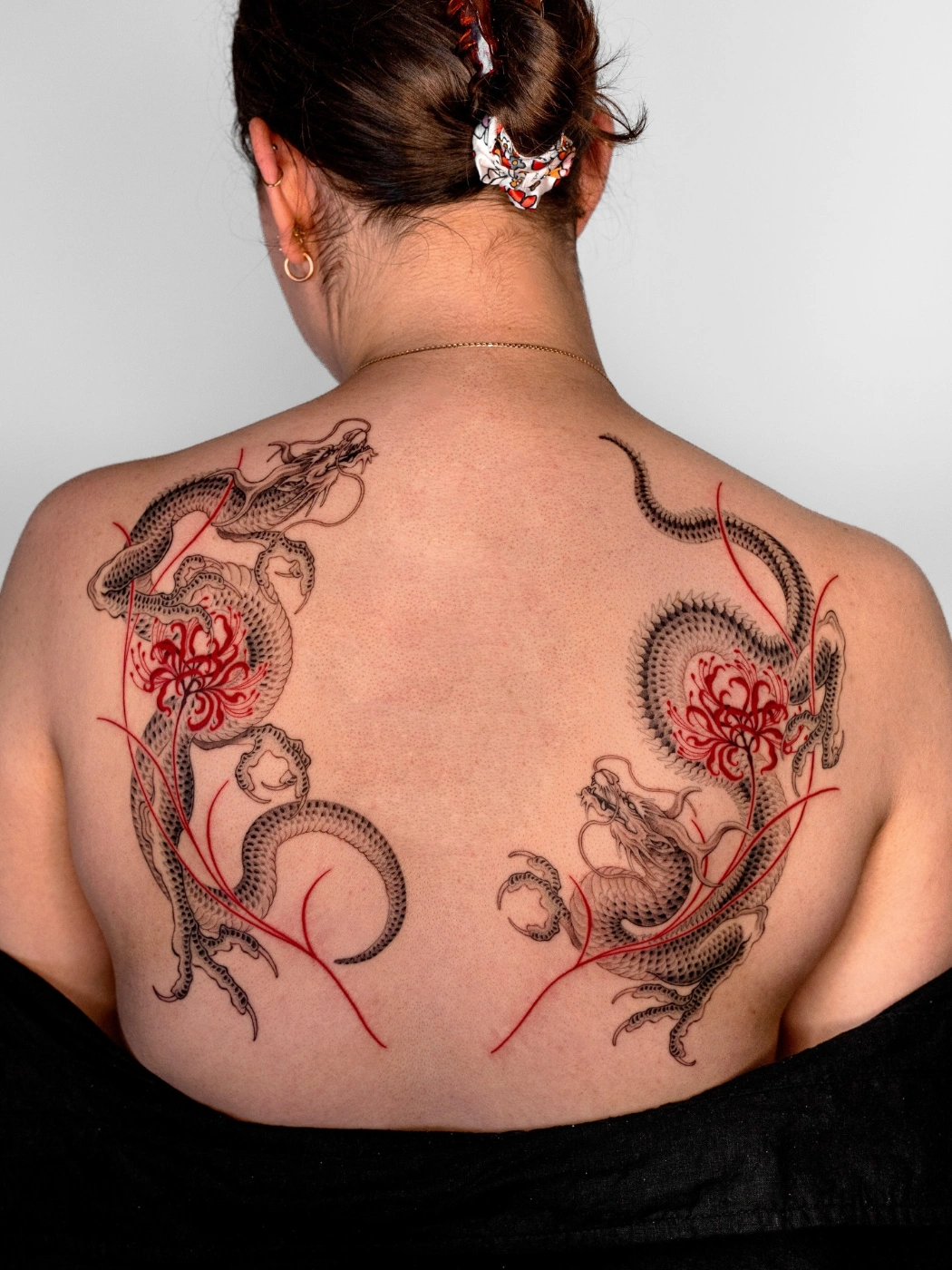 Large back tattoo featuring dragons and flowers in black and red.