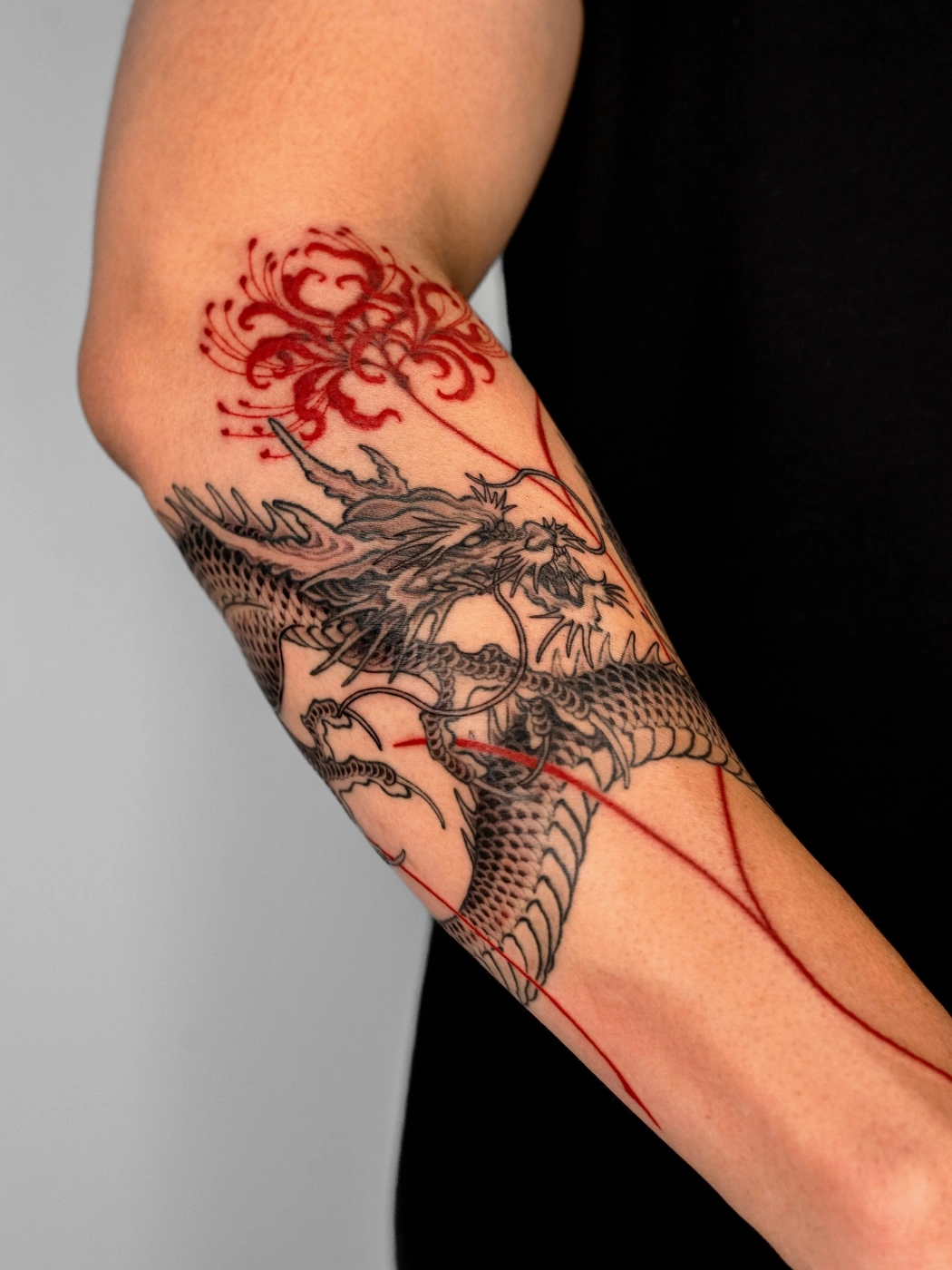 Detailed dragon tattoo with floral elements on forearm.