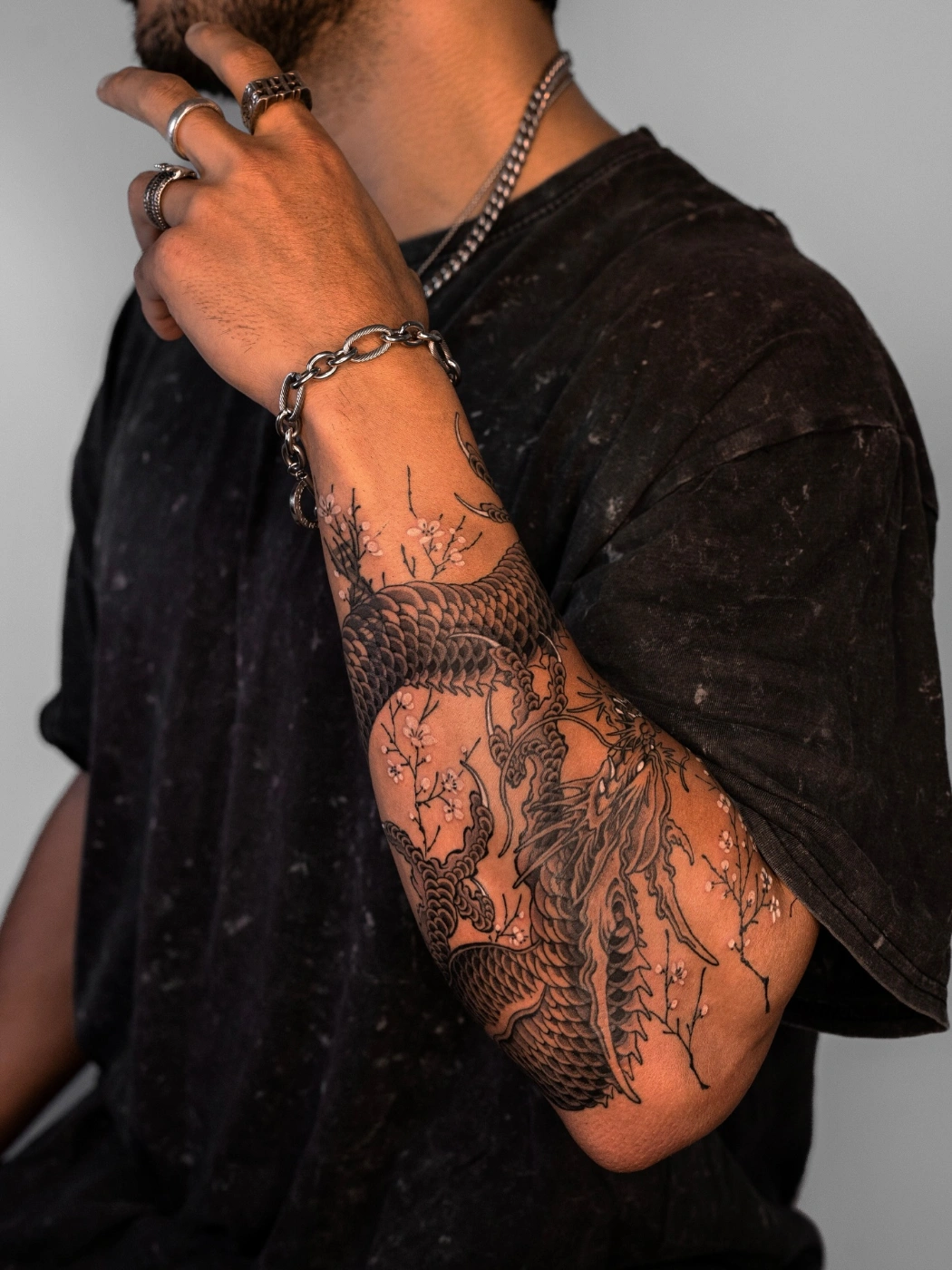 Illustrative dragon tattoo on forearm with floral elements.
