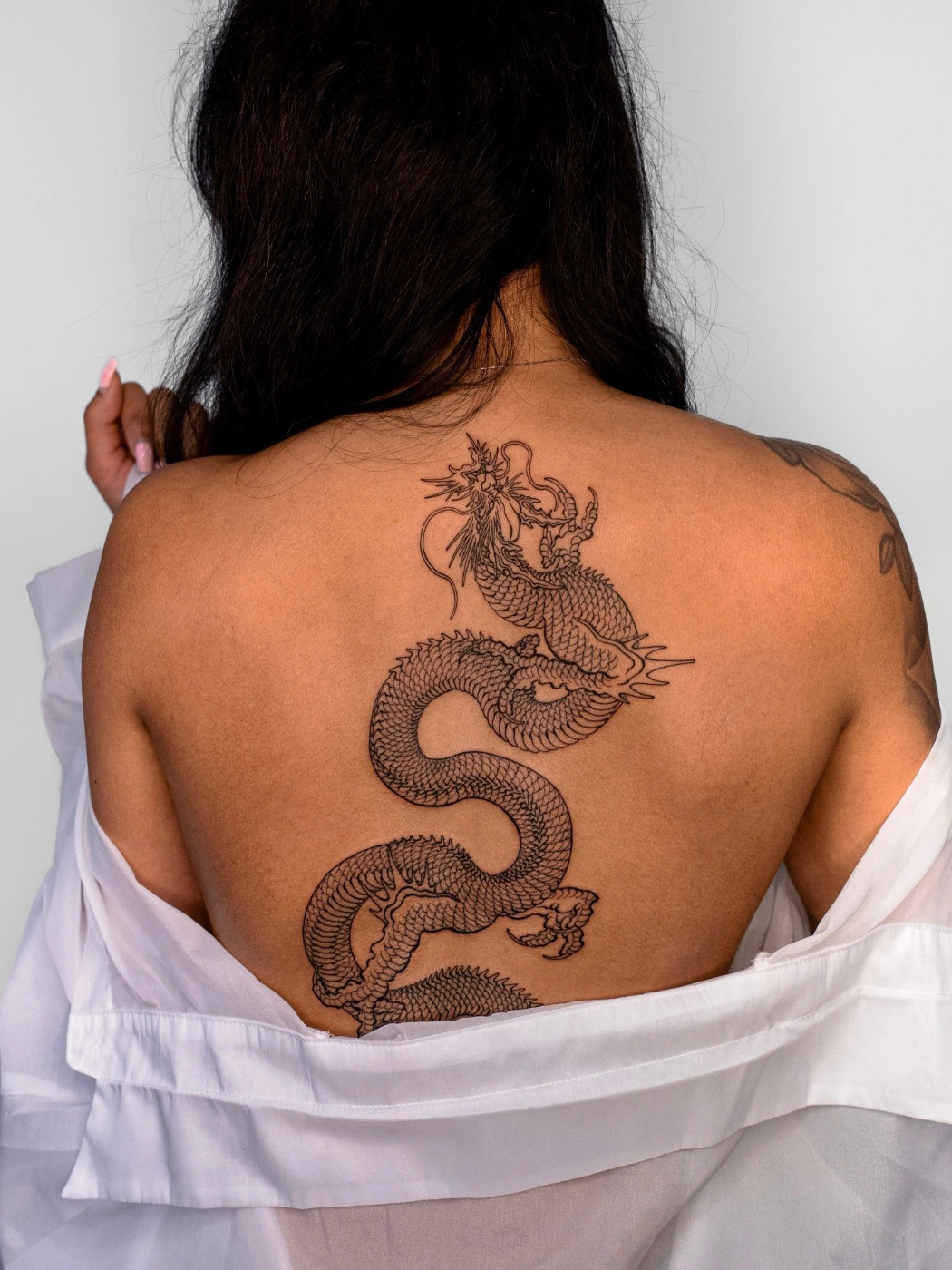 Large blackwork dragon tattoo on a woman's back.