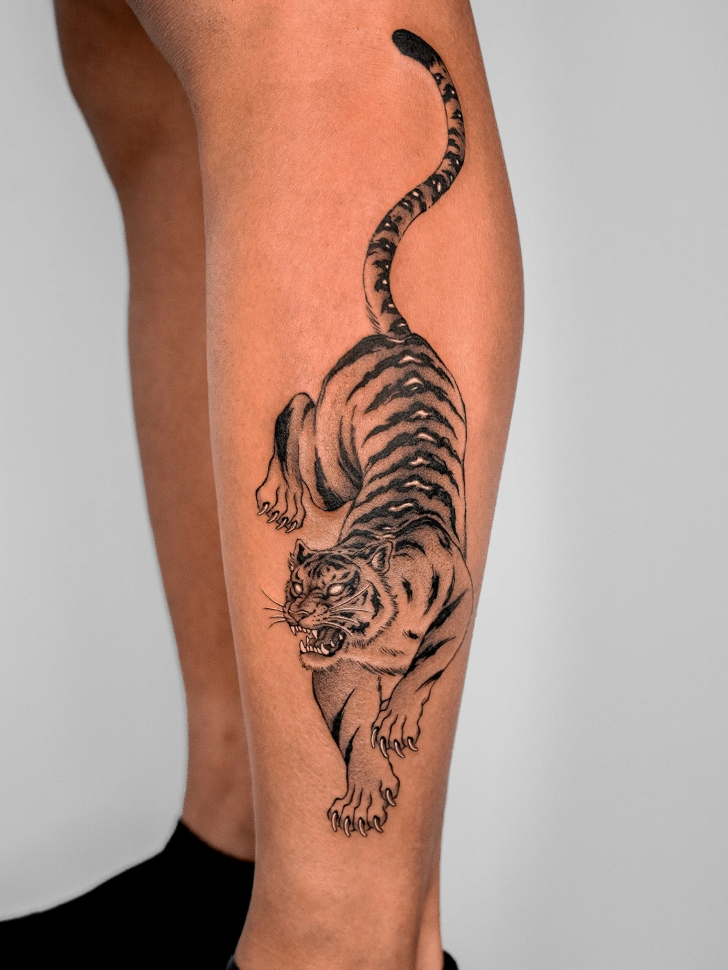 Realistic black-and-grey tiger tattoo on calf.