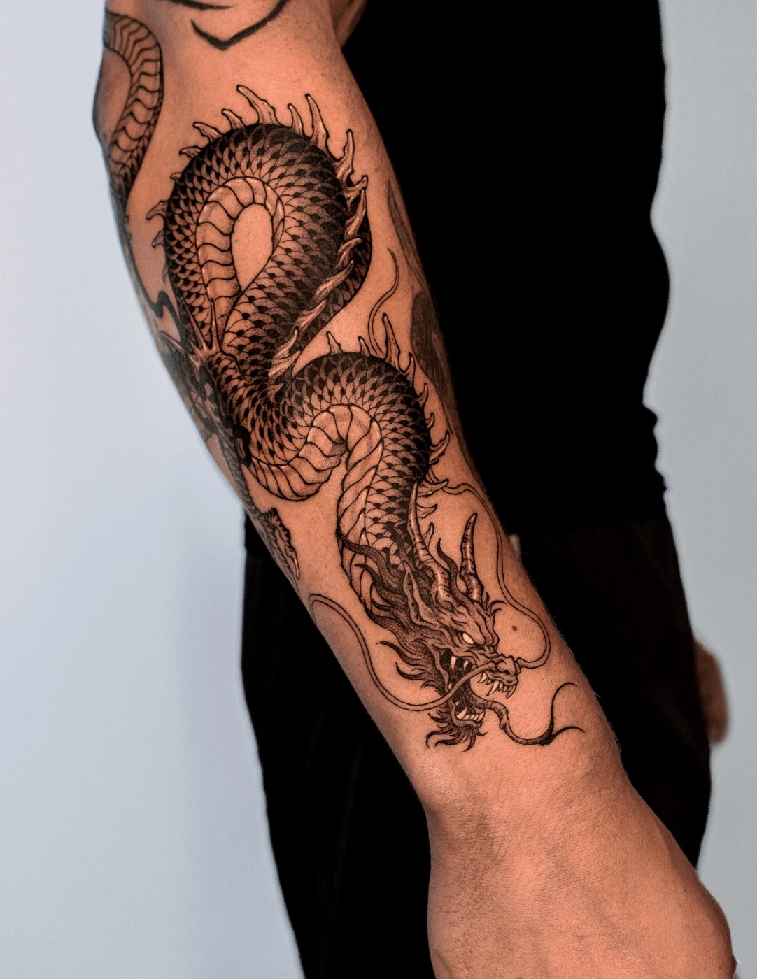 Large blackwork dragon tattoo on forearm.
