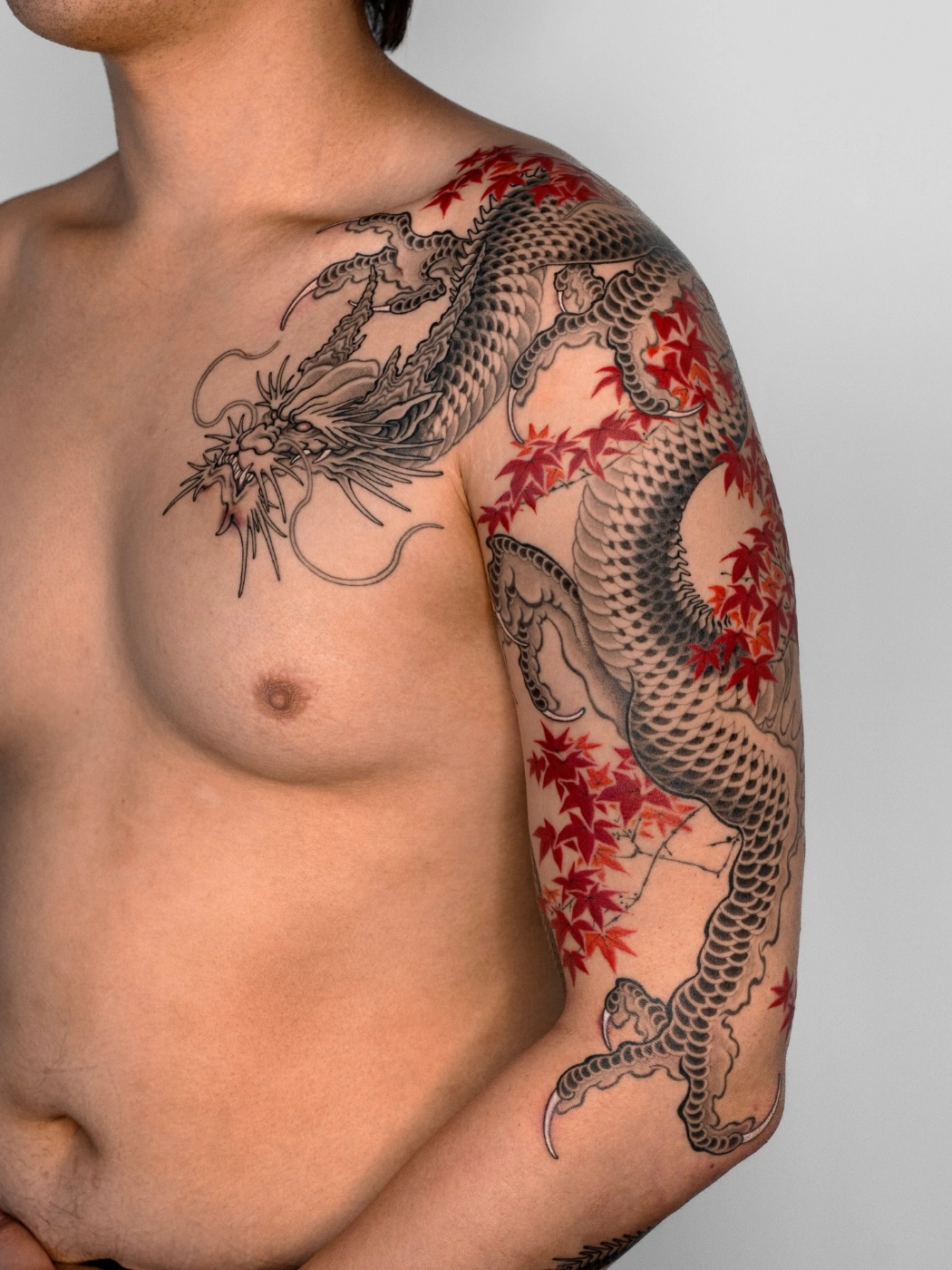 Large Japanese dragon tattoo with maple leaves on arm.