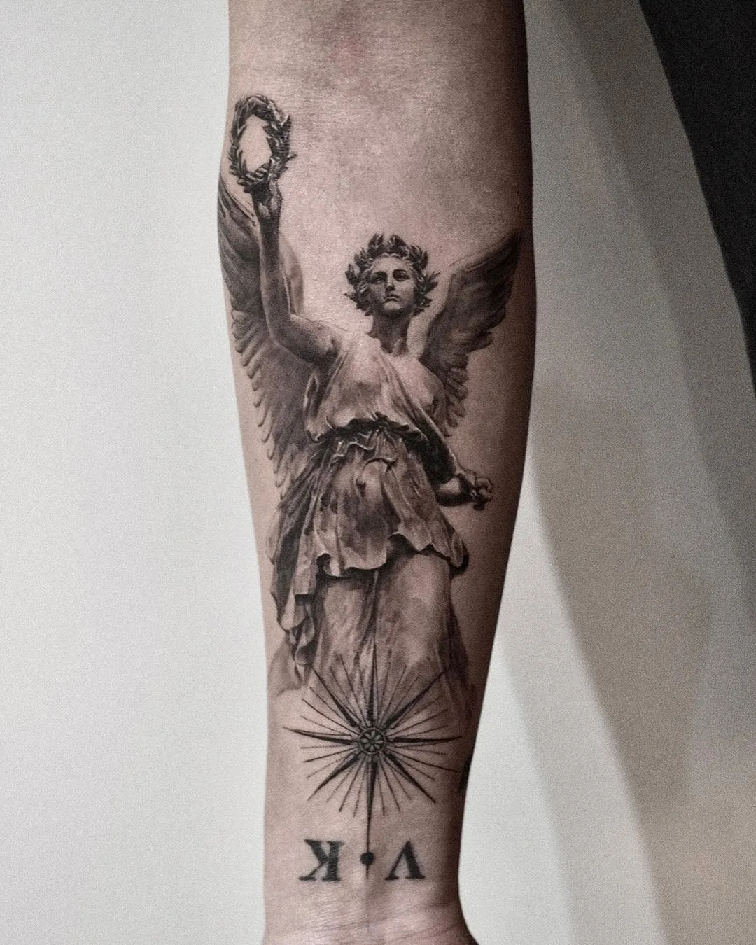 Detailed black-and-grey angel tattoo on forearm.