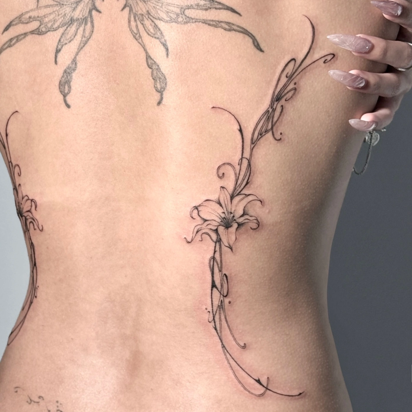 Elegant fine-line floral tattoo on a woman's back.