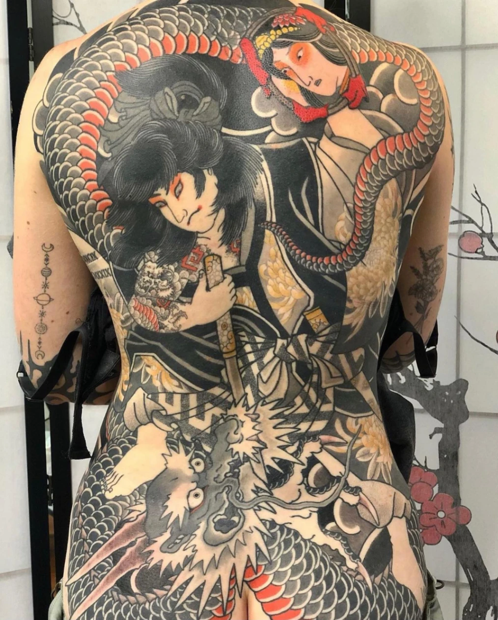 Large Japanese tattoo on back featuring dragon and geisha.