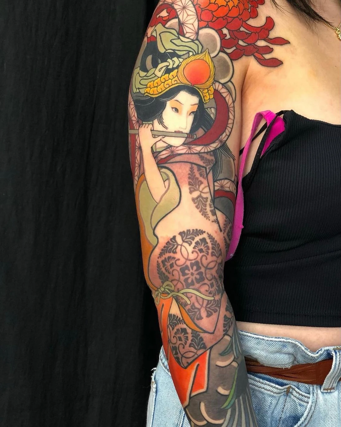 Colorful full-sleeve tattoo of a geisha on an arm.