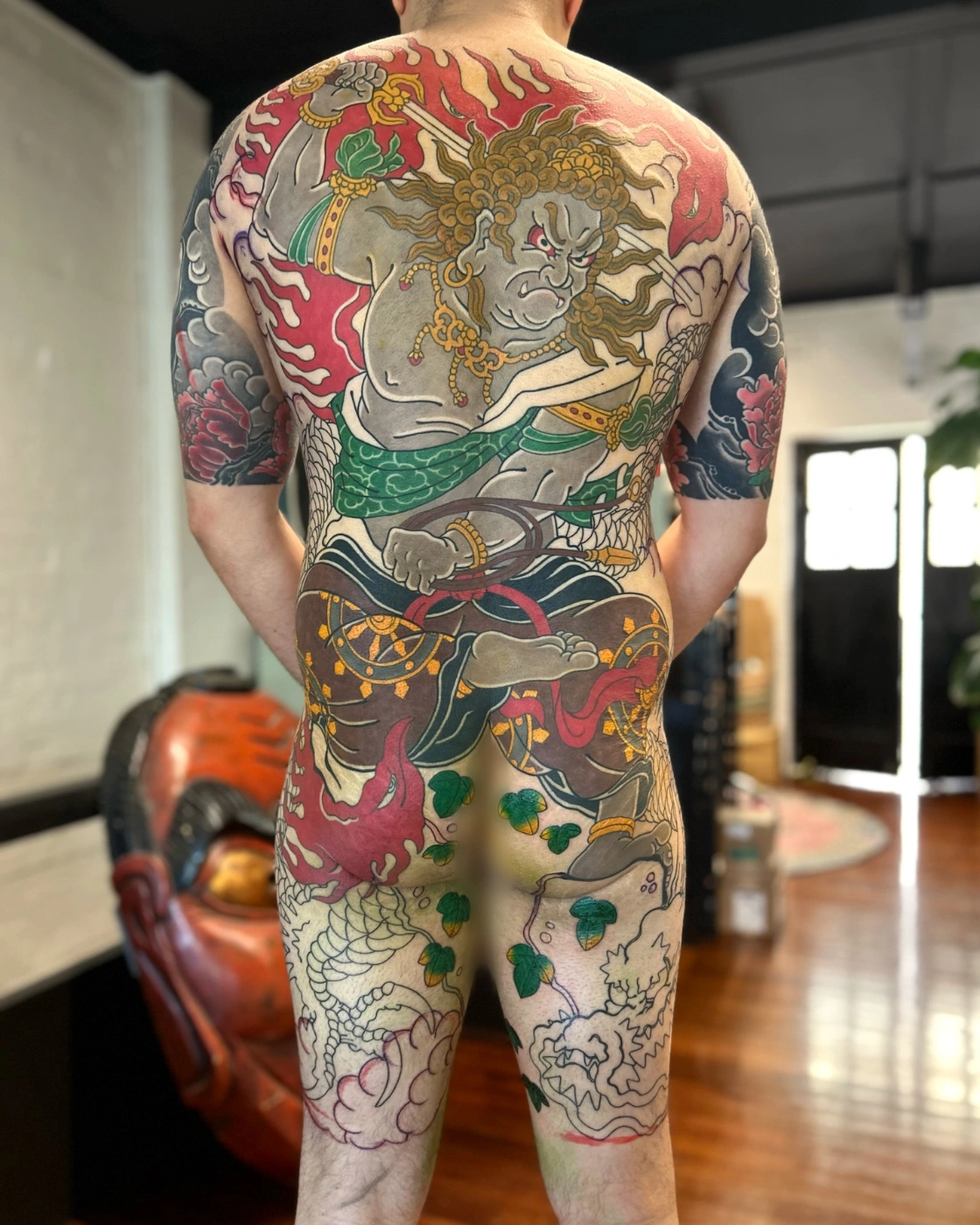 Large Japanese tattoo on a man's back featuring dragons and flames.