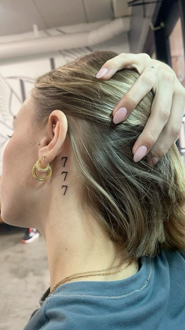 minimalist 777 tattoo behind the ear