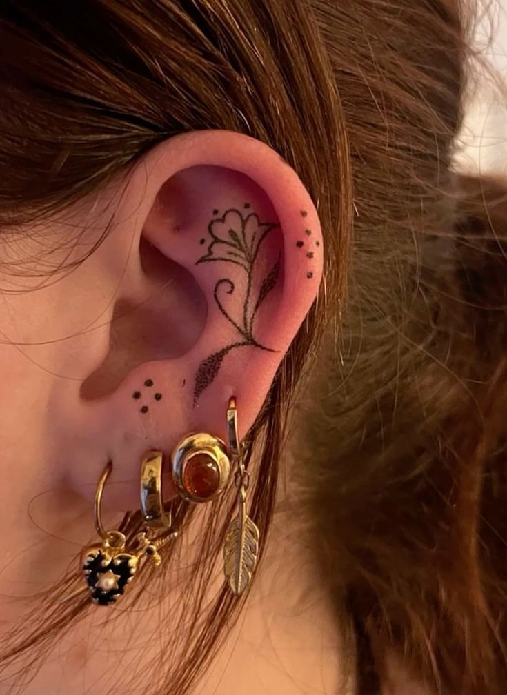 a close up of a person's ear with tattoos on it and an ear piercing