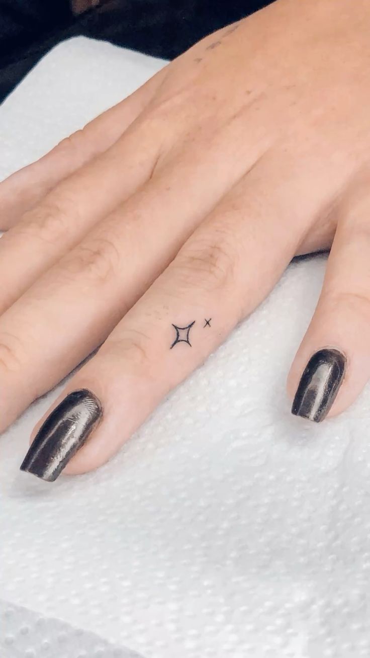 minimalist finger tattoo design with star and cross