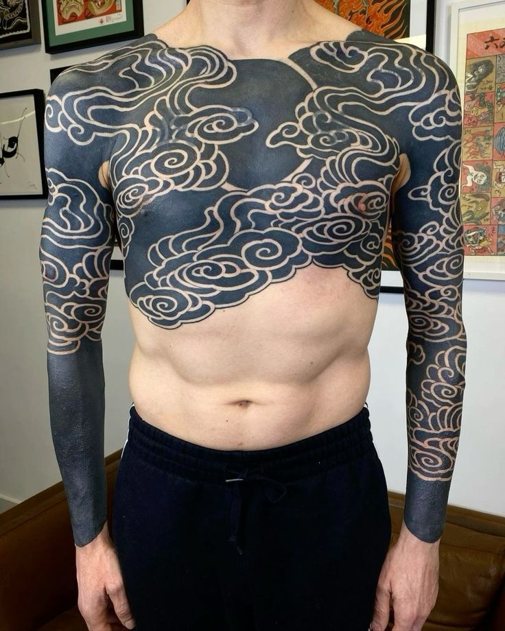 a man with tattoos on his chest and arms
