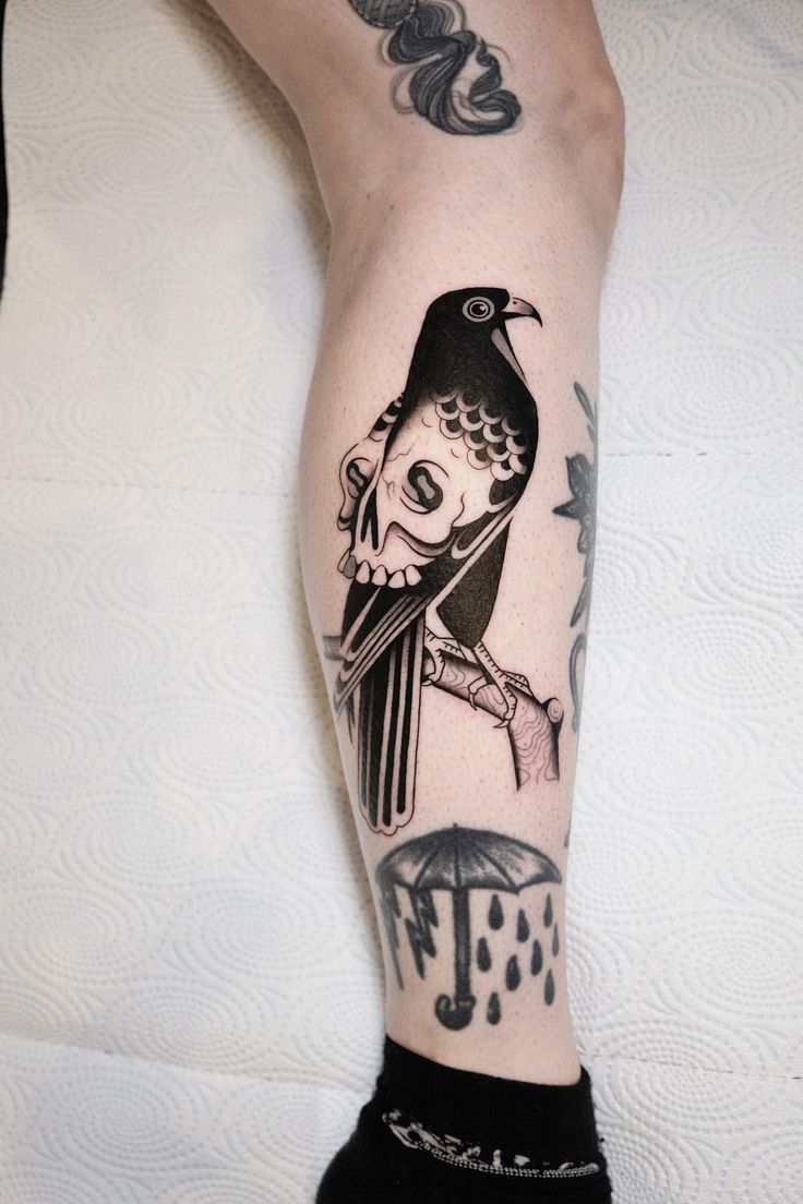 a tattoo on the leg of a person with a bird and an umbrella in it