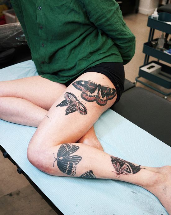 a woman sitting on top of a table covered in tattoos