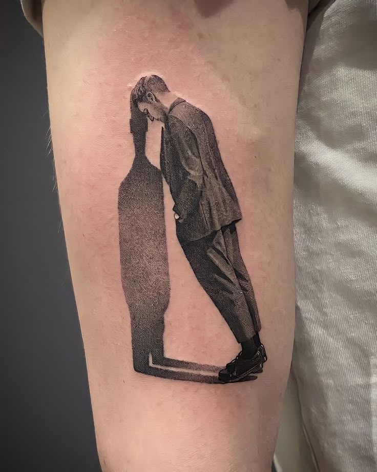 a man in a suit and tie standing next to a bottle tattoo on his arm